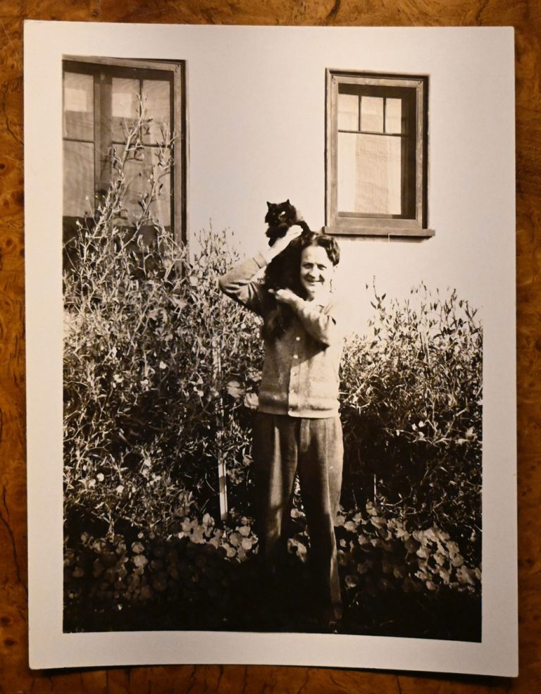 Raymond Chandler holding Taki’s tail still for a photograph in La Jolla
